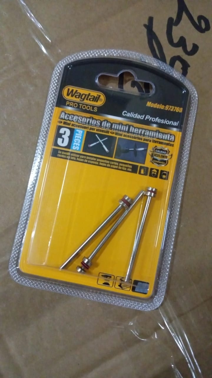 A clear plastic blister pack with a yellow card containing three silver mandrels with red bands, resting on a brown surface.