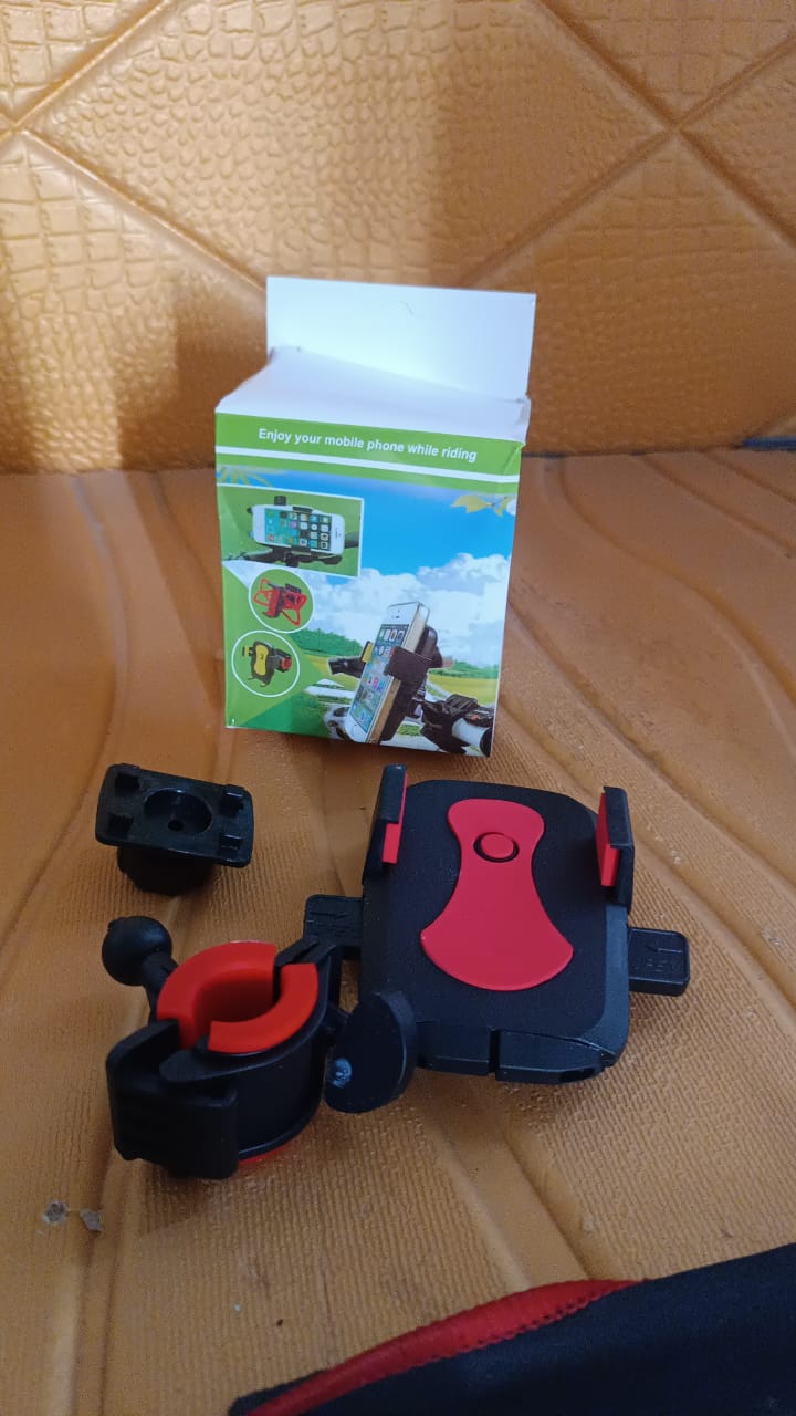 Black and red phone mount components and its green and white packaging box on a brown textured surface.