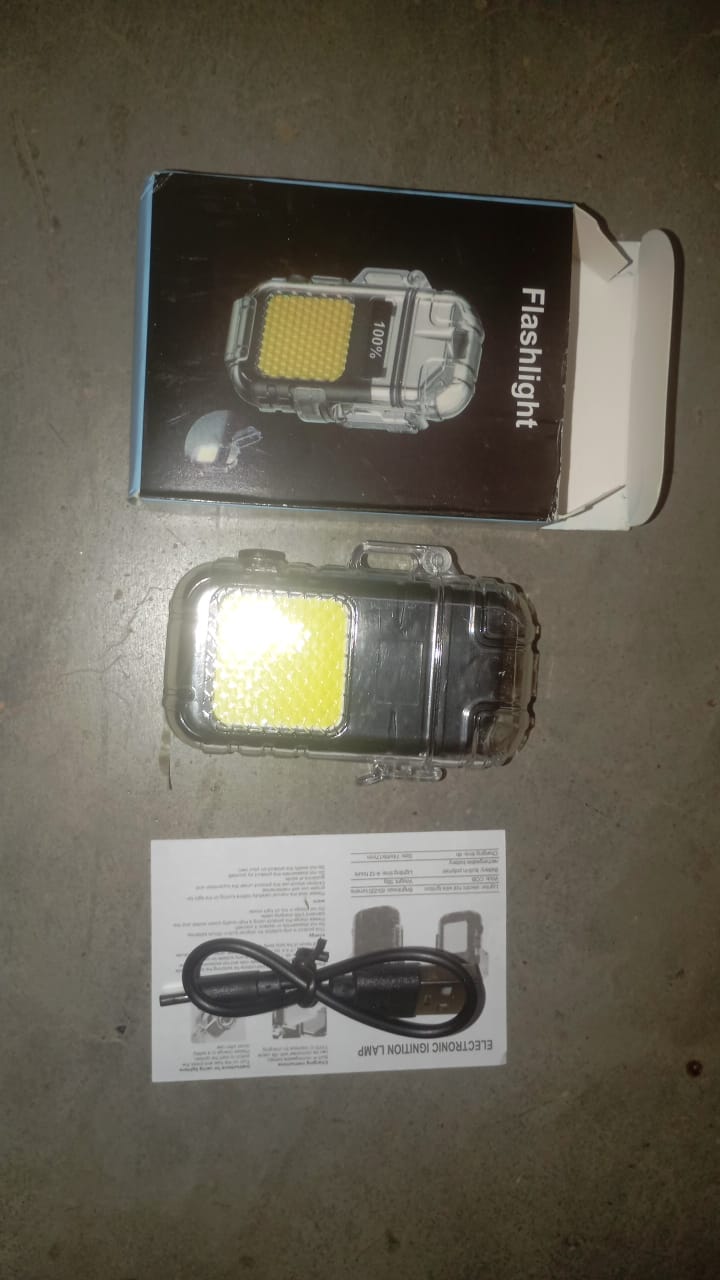 The clear waterproof electric lighter and flashlight is displayed with its packaging box, a USB charging cable, and