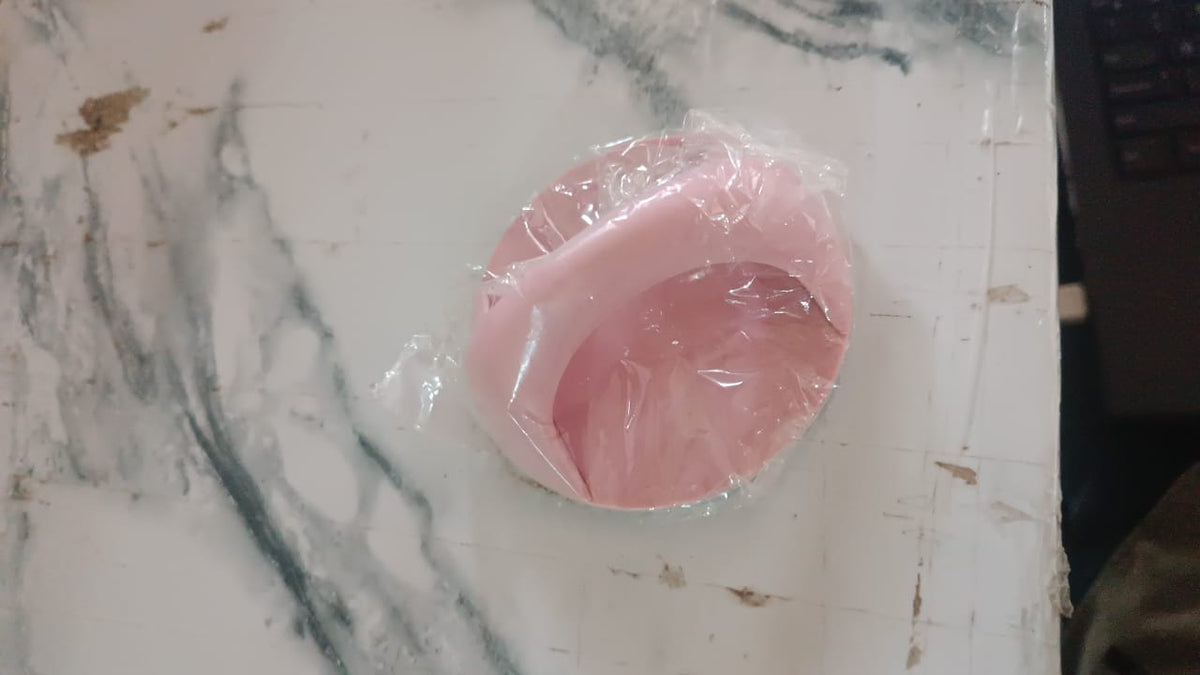 A pink self-adhesive handle is wrapped in clear plastic on a white and gray marble surface.