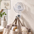 A clear octagonal self-adhesive wall hook with a silver hook, holding a beige tote bag filled with towels and toiletries, on