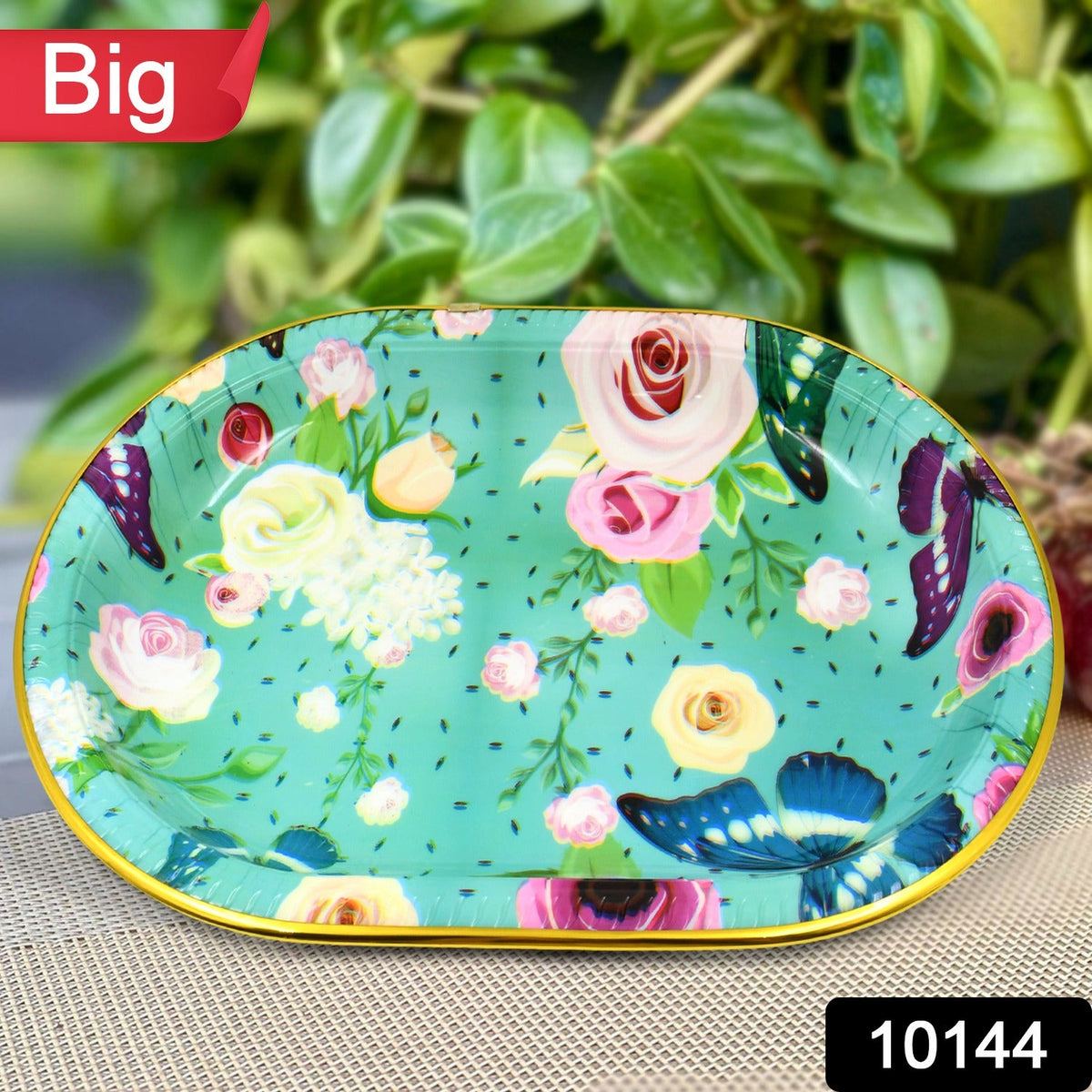 Close-up of the oval turquoise tray with a vibrant floral and butterfly pattern, with a green background.