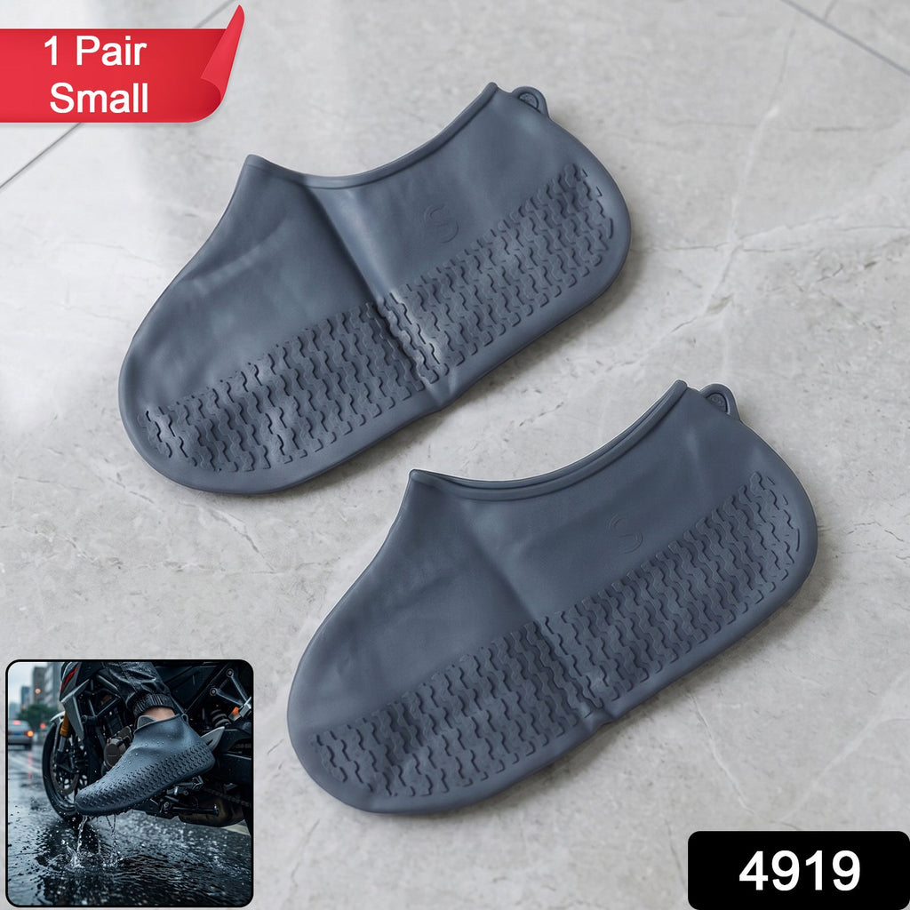 Two small grey silicone shoe covers with textured soles are displayed on a light grey tiled surface, with a small inset